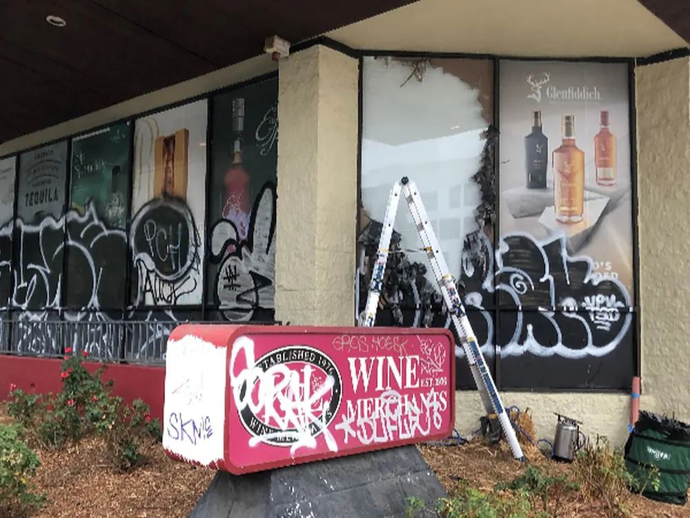 Storefront glazing covered in tagging, mid-way through a film replacement.